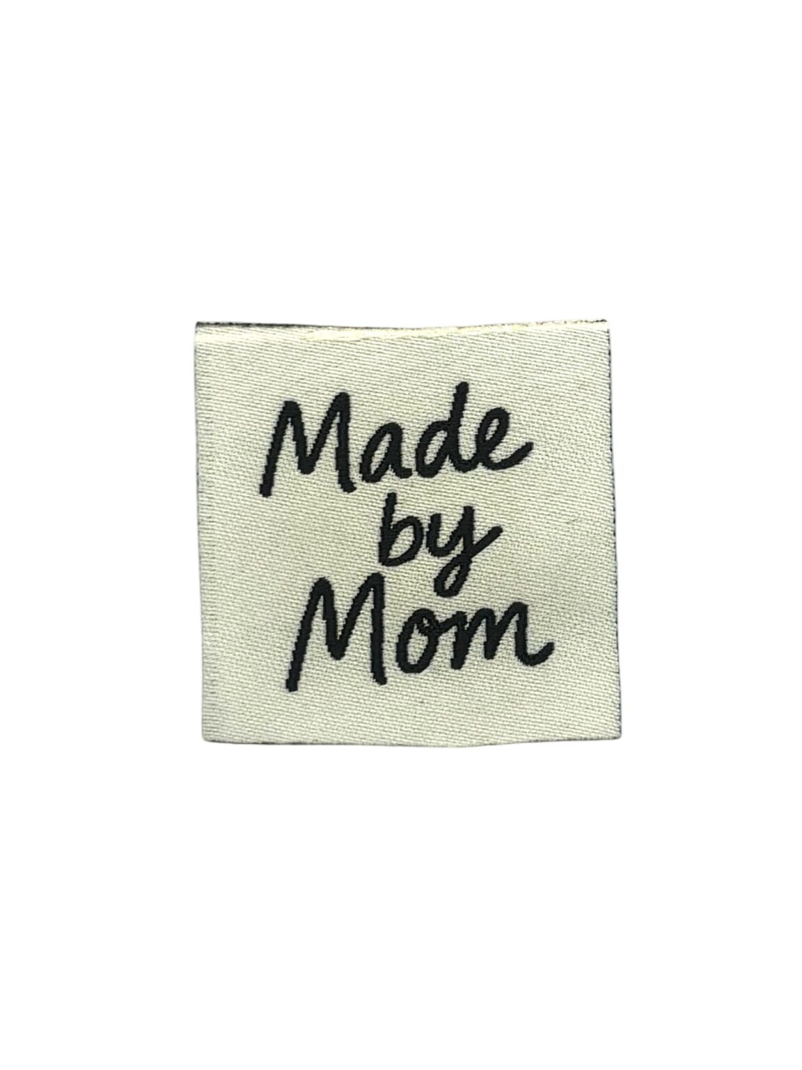 Wit textiellabel met zwart geborduurde tekst Made by Mom op kledingstuk