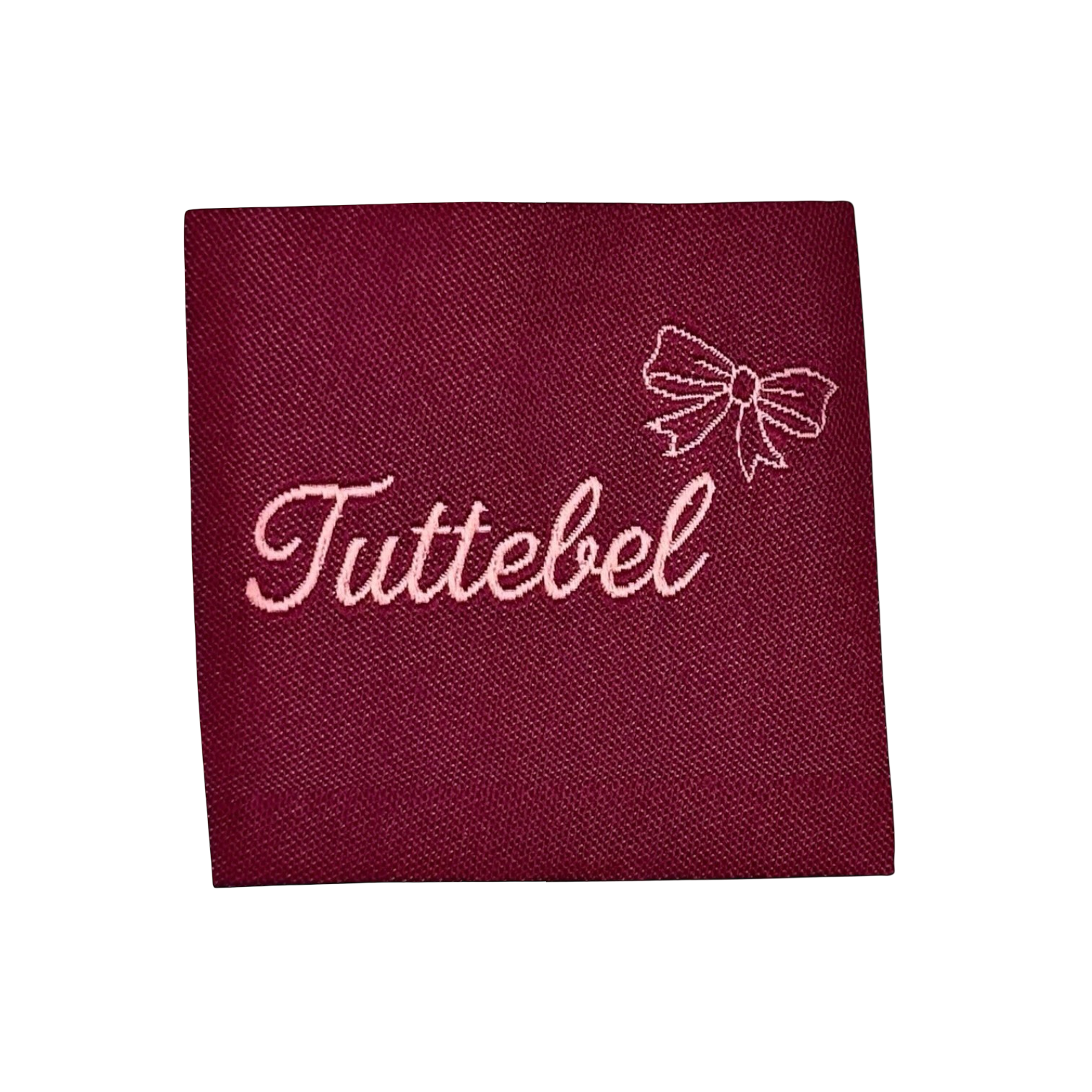 Bordeauxrood stoffen label met roze geborduurd opschrift 'Tuttebel' en strikje